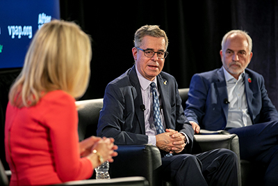 Three people discuss politics on a stage.