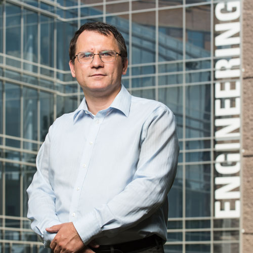 Mihai Boicu wears a light-blue shirt and stands in front the Nguyen Engineering building in his faculty profile for the Department of Information Sciences and Technology.
