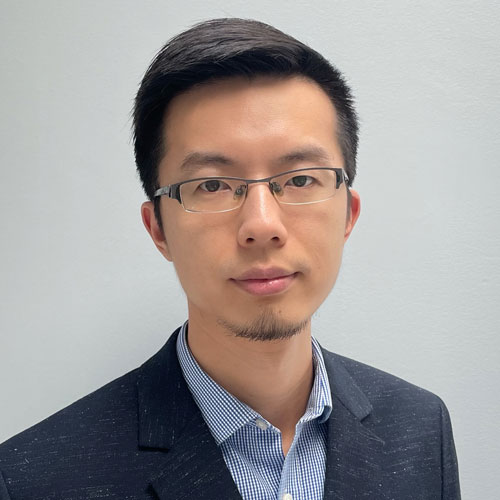 Zhisheng Yan wears a navy suit and blue shirt and glasses in his faculty profile for the Department of Information Sciences and Technology.
