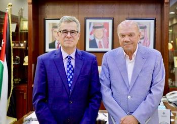 Two men in blue suits look at the camera.